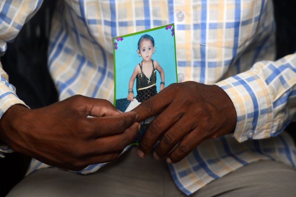 Мохамед Захид держит фотографию своего пятилетнего ребенка по имени Хуши в черном платье