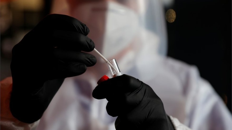 A health worker, wearing a protective suit and a face mask, holds a test tube after administering a nasal swab to a patient in a temporary testing site for the coronavirus disease (COVID-19) at the Zenith Arena in Lille, France, October 15, 2020.