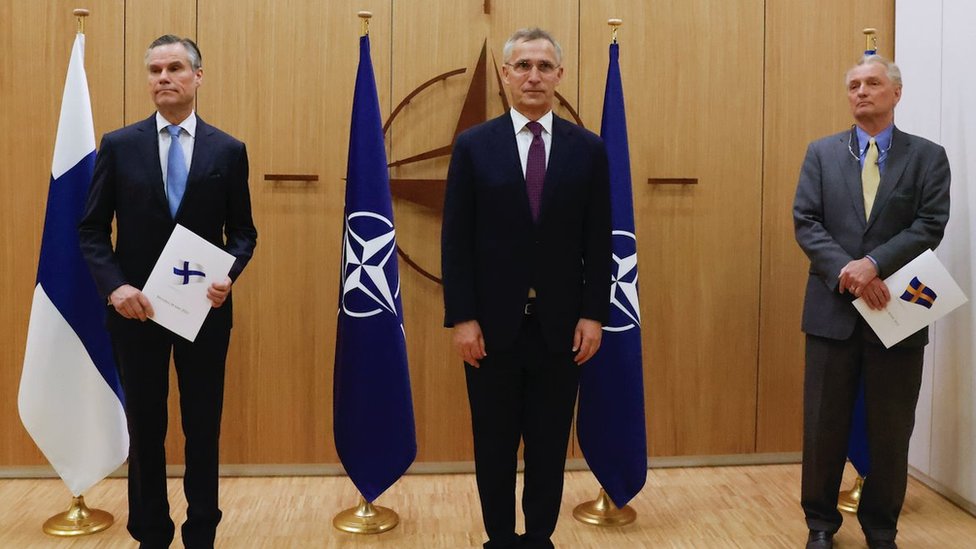Finland's Ambassador to NATO Klaus Korhonen, NATO Secretary-General Jens Stoltenberg and Sweden's Ambassador to NATO Axel Wernhoff pose during a ceremony to mark Sweden's and Finland's application for membership in Brussels, on May 18, 2022