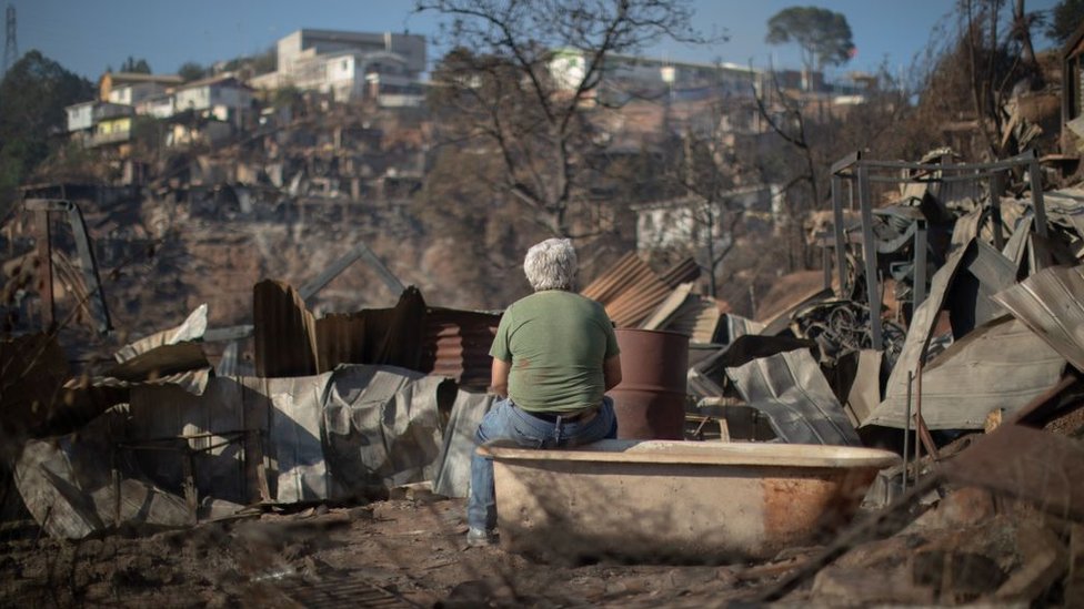 Un hombre sentado en una bañera mira la desolación tras el fuego en Valparaíso.