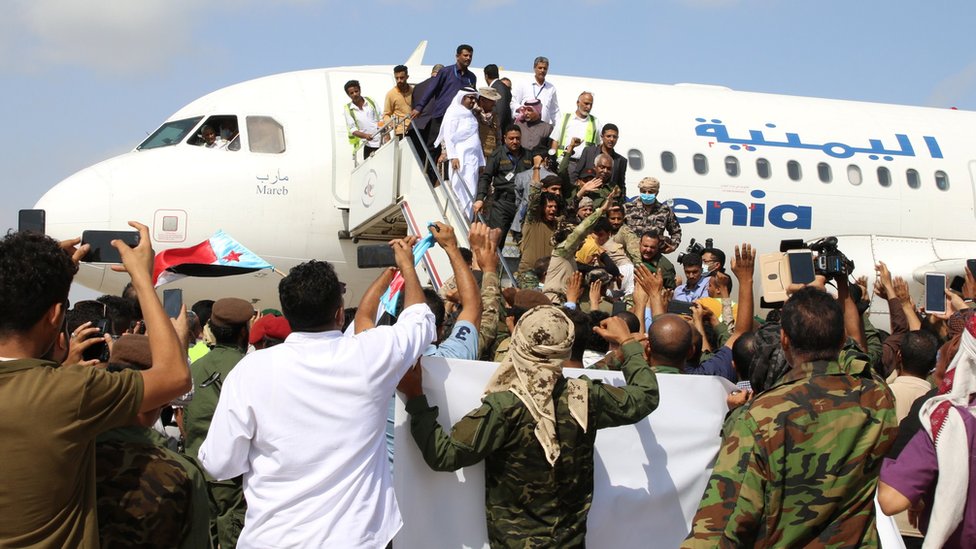 People take photos of passengers getting off a plane at Aden airport on 30 December 2020