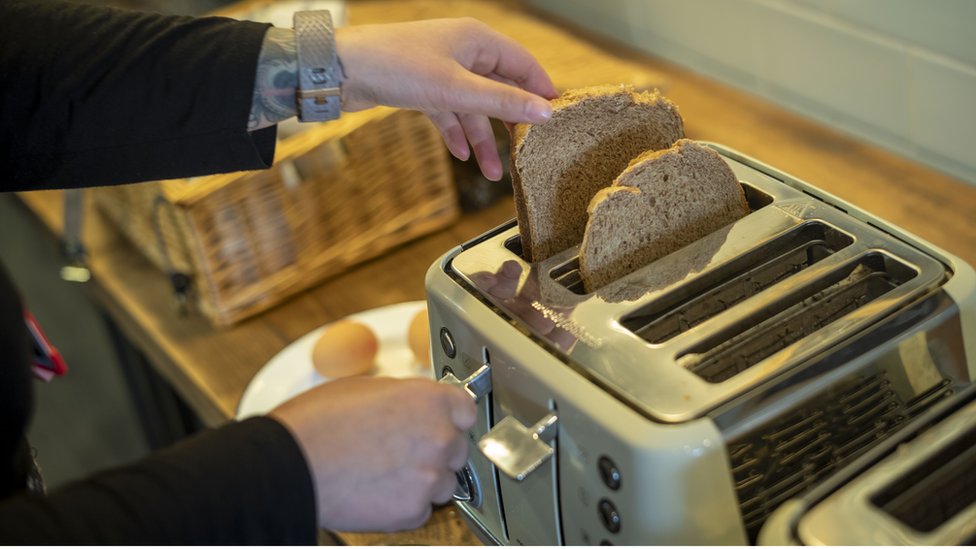 Женщина кладет хлеб в тостер
