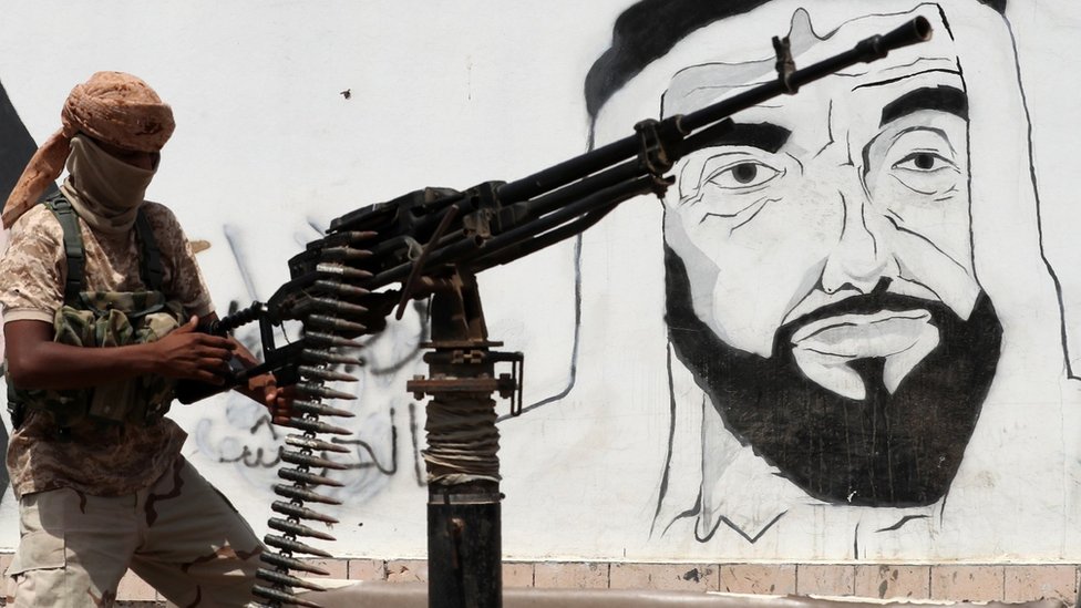 Поддерживаемый ОАЭ проправительственный боец ??Йемена держит пулемет рядом с фреской в ??Мукалле, на которой изображен покойный основатель и президент ОАЭ шейх Зайед бин Султан Аль Нахайян (8 августа 2018 г.)