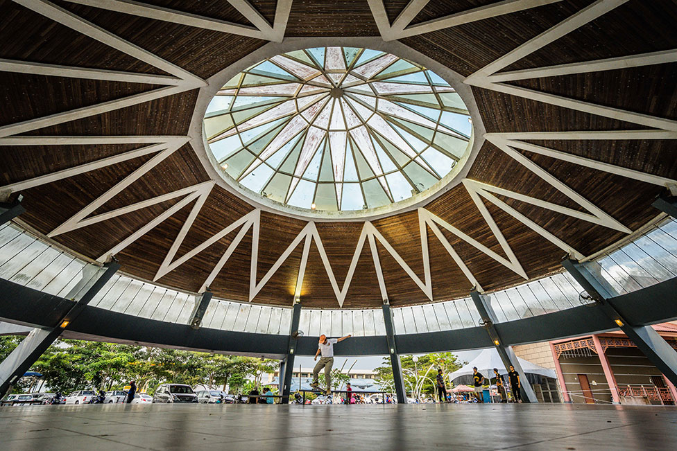 The large roof of a building in Kuching, Malaysia, with a skateboarder beneath