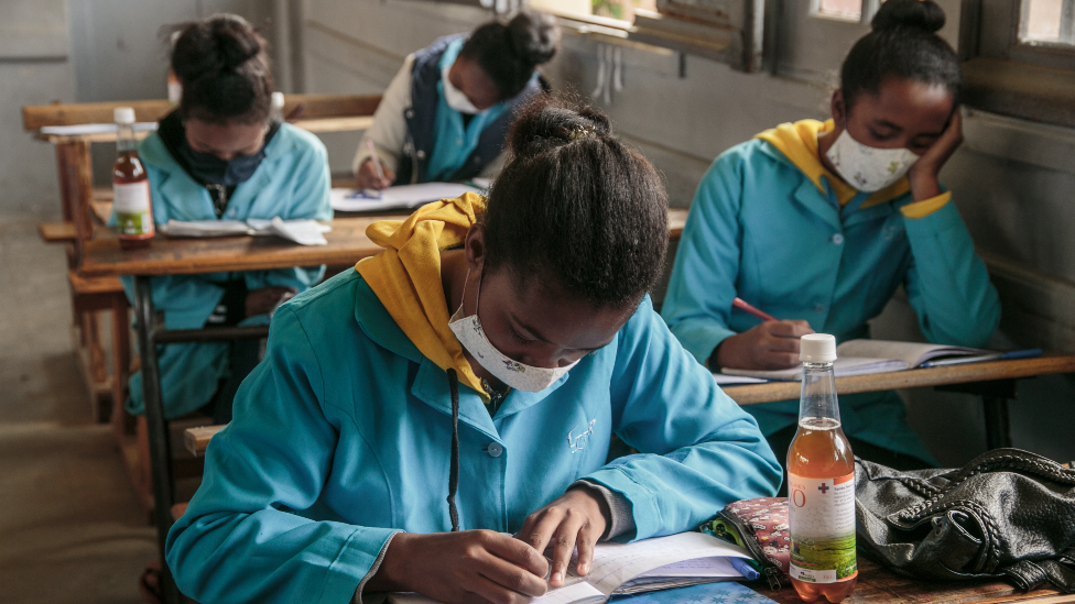 Anak sekolah di Madagaskar sedang belajar dan di meja mereka terdapat botol Covid-Organics April 2020