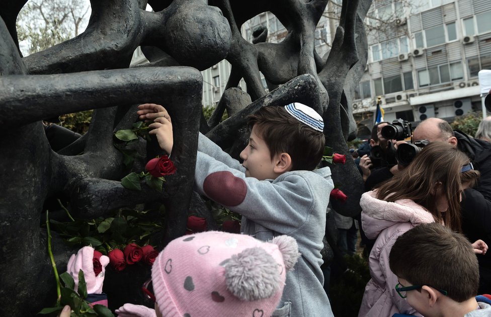 Ребенок возлагает розы к мемориалу Холокоста в Салониках