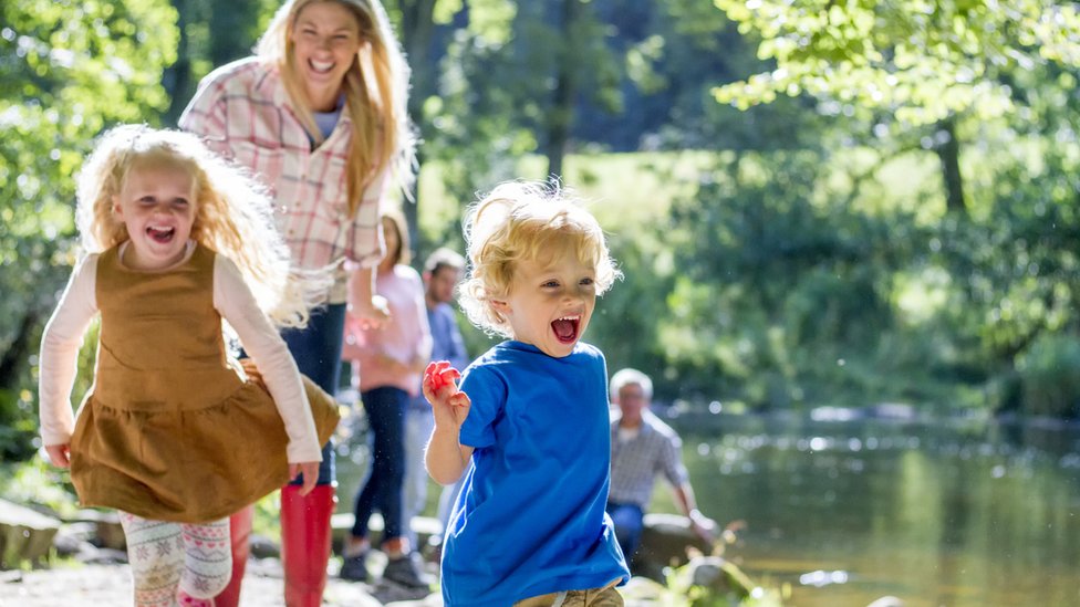 La mayoría de la gente recuerda más cosas buenas que malas y por eso sobrestima su calidad de vida, alega el filósofo. Niños y su madre sonrientes se divierten cerca de un río