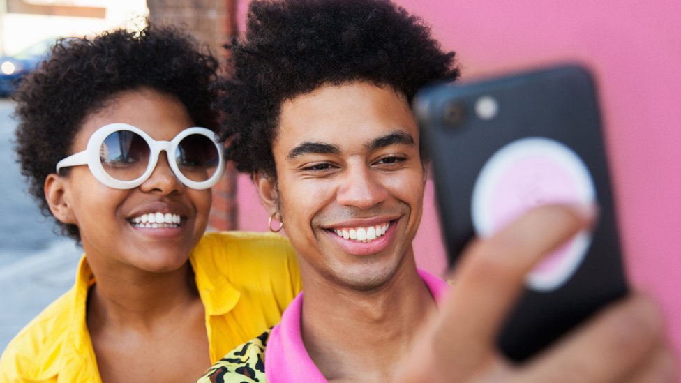Una pareja sonríe al tomarse una selfie.
