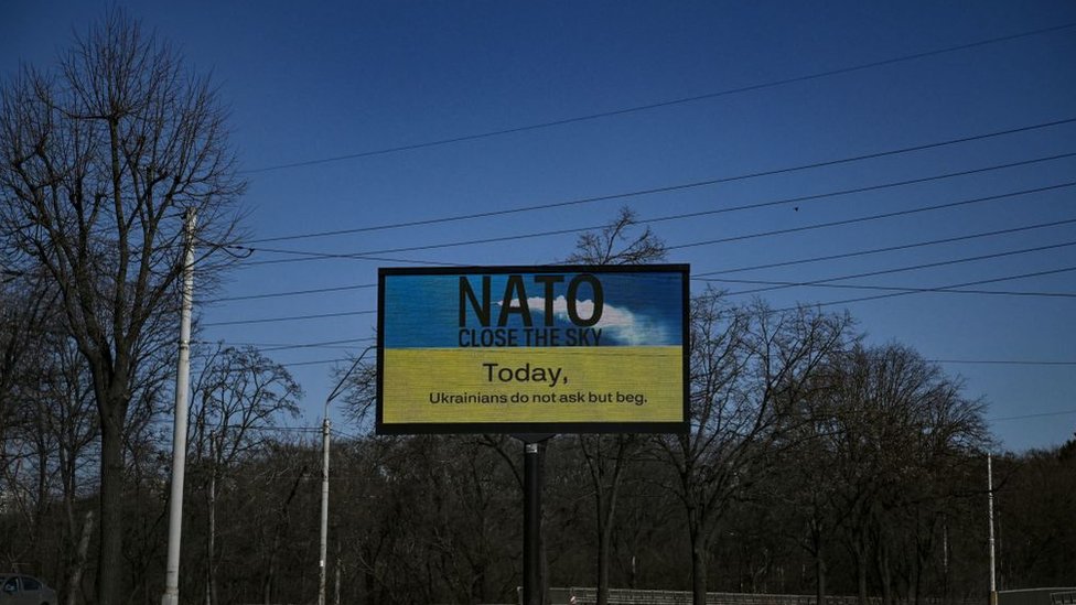 Una fotografía tomada el 22 de marzo de 2022 muestra un cartel que dice "OTAN, cierra el cielo hoy" en una avenida vacía durante un toque de queda de 36 horas en Kiev.