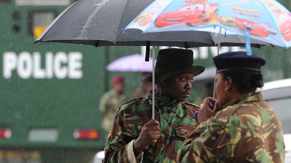 Кенийская полиция защищает себя от дождя 14 ноября 2017 г. у здания Верховного суда в Найроби
