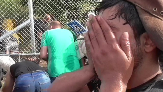 Man holding hands to his face after Hungarian police use tear gas to force back migrants on the Serbian-Hungarian border
