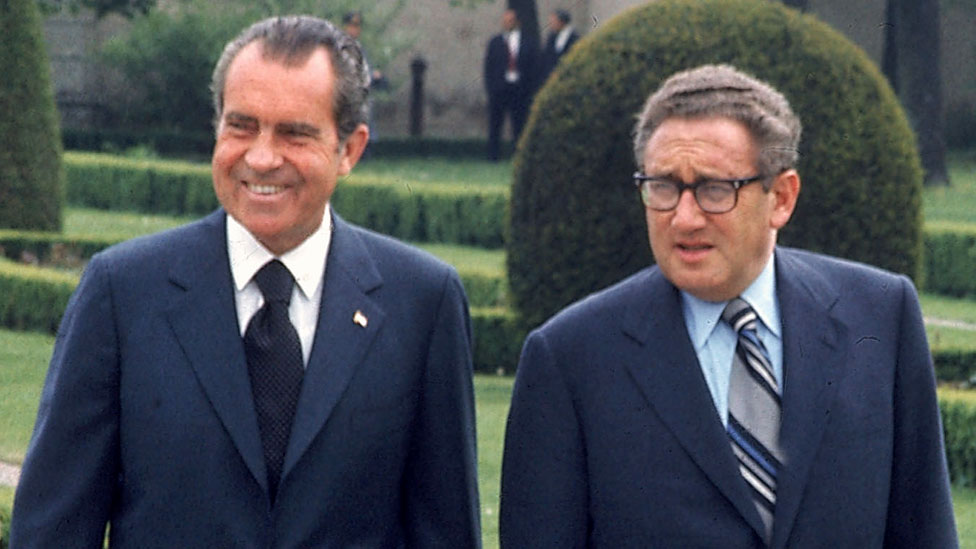 President Richard M. Nixon and Secretary of State Henry Kissinger strolling through a park during visit to Austria in 1972
