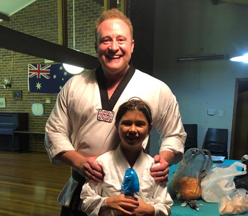 Charles con su hija y vestidos con uniformes de artes marciales.