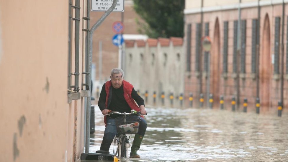 A man cycles through flood water in Lugo, near Ravenna, Italy, 18 May 2023