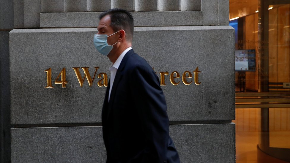 Мужчина в защитной маске идет по Уолл-стрит, 14, в то время как глобальная вспышка коронавирусной болезни (COVID-19) продолжается в финансовом районе Нью-Йорка, США., 19 ноября 2020 г.