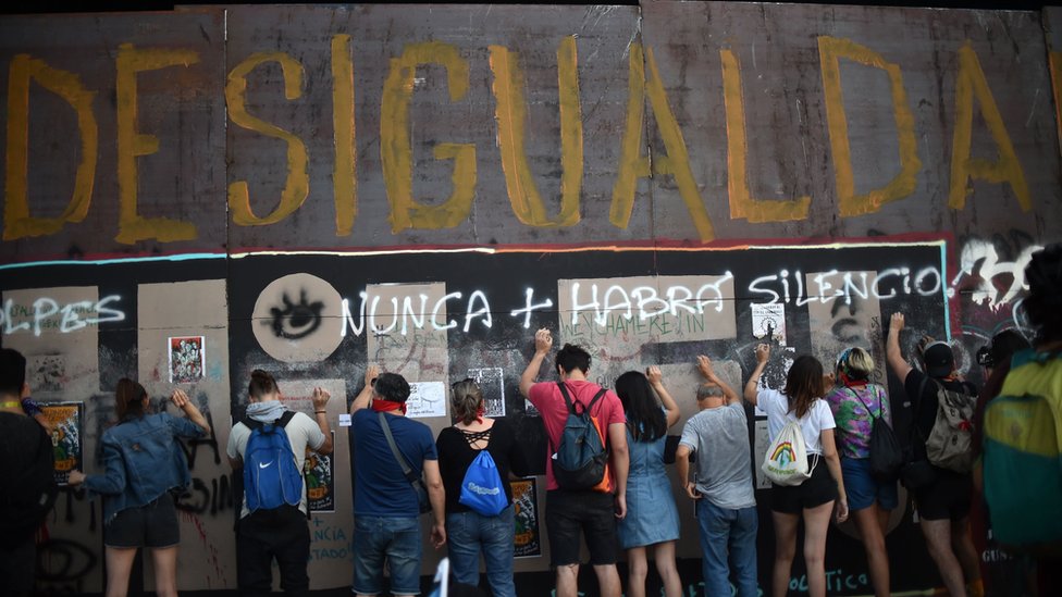 Люди проводят демонстрацию под надписью «Неравенство» во время акции протеста с требованием более серьезных социальных реформ от президента Чили Себастьяна Пинеры в Сантьяго 12 ноября 2019 года.
