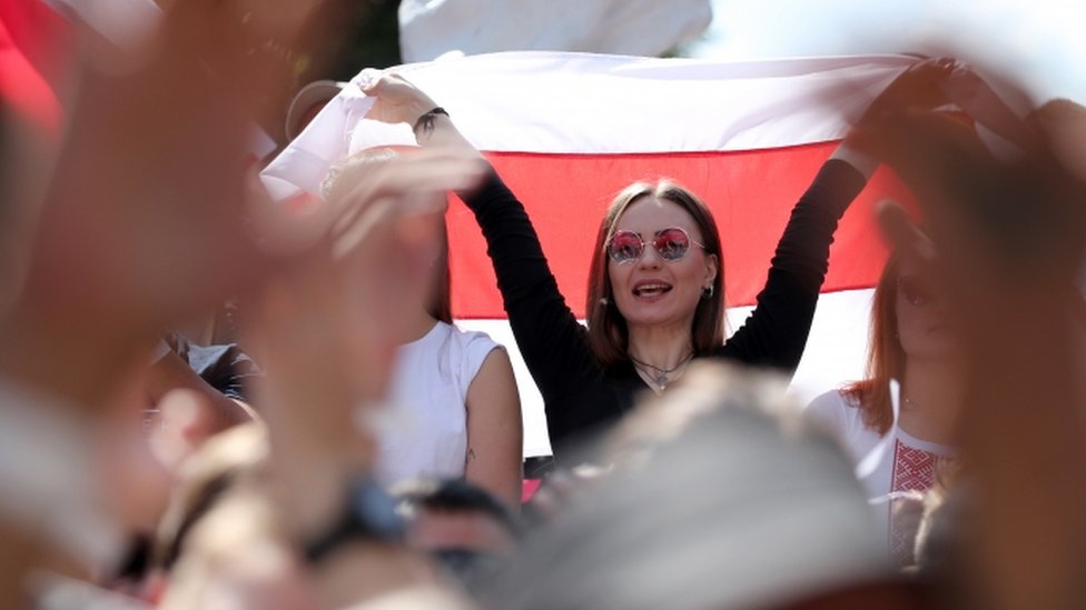 Светлана Тихановская держит флаг на митинге