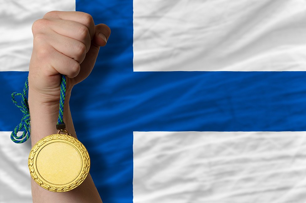 Bandera de Finlandia con un brazo delante sosteniendo una medalla de oro