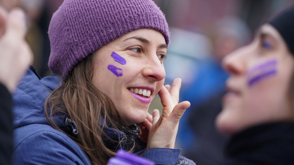 Uma mulher pinta listras roxas no rosto durante um protesto feminista no Dia Internacional das Mulheres em 08 de março de 2020 em Berlim, na Alemanha