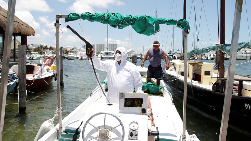 Сотрудник частной компании дезинфицирует лодку на пристани в Канкуне