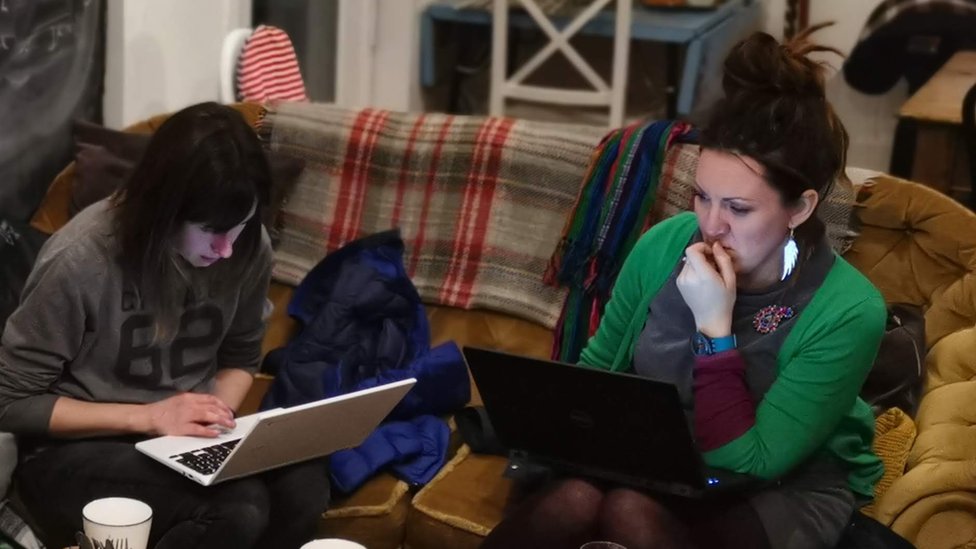 Два добровольца редактируют Википедию на мероприятии в Мачинлете, сидя на диване в кафе с ноутбуками