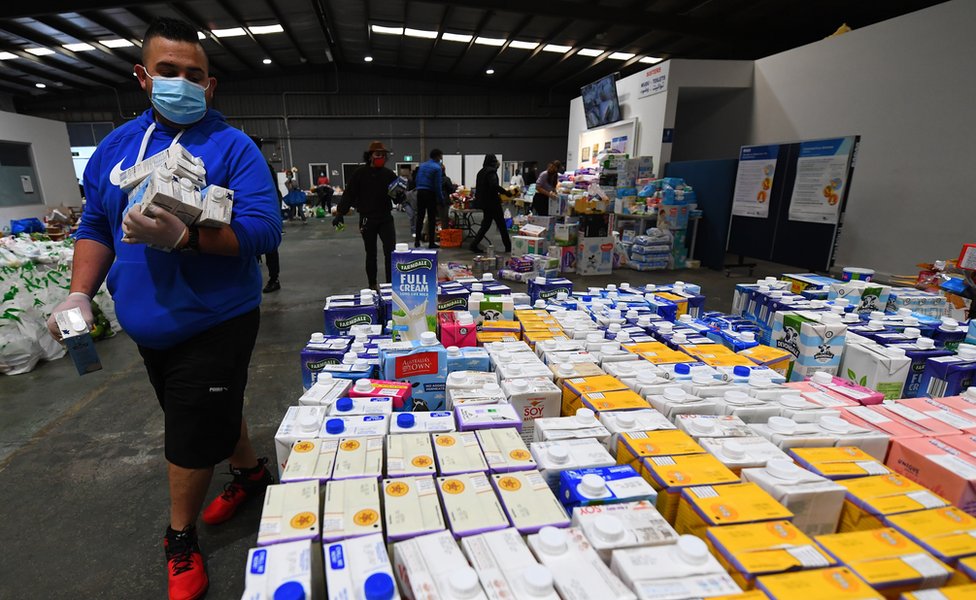 Волонтер помогает организовать пожертвованные продукты питания