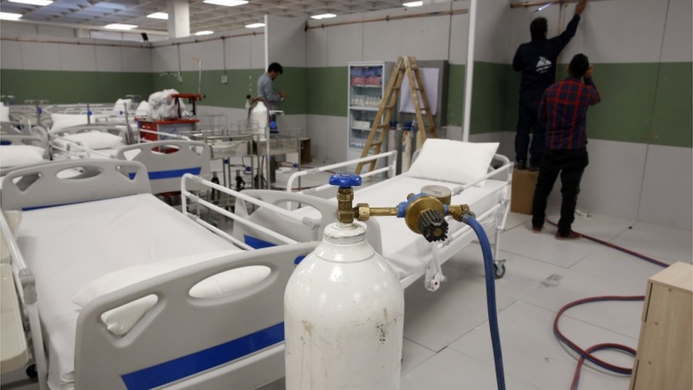 Trabajadores instalan un hospital de emergencia en un centro comercial en Teherán, India.