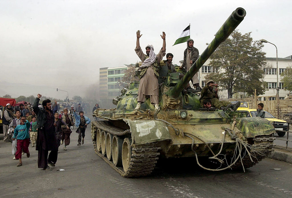 Coalition-backed Northern Alliance fighters ride tanks into Kabul as the Taliban retreat
