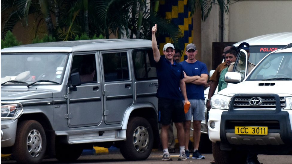 Член британской команды по борьбе с пиратством Джон Армстронг (слева) показывает рукой своему коллеге Нику Симпсону, когда они выходят из тюрьмы в Ченнаи