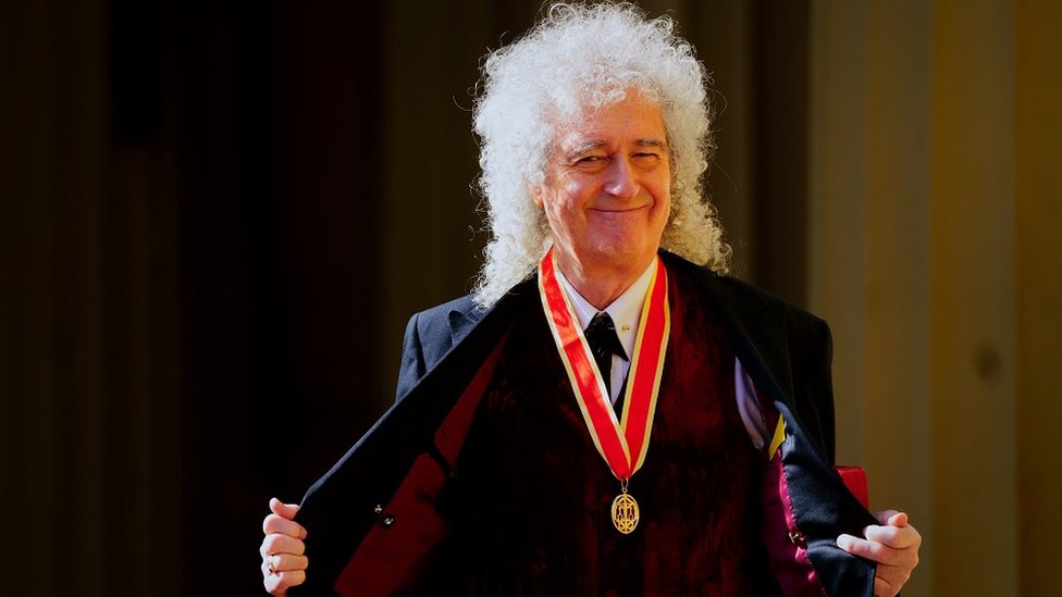 Brian May smiles to the camera after being knighted