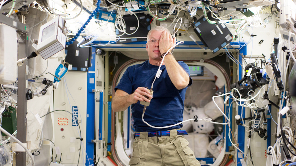 Astronauta Steve Swanson cubriendo uno de sus ojos con una mano