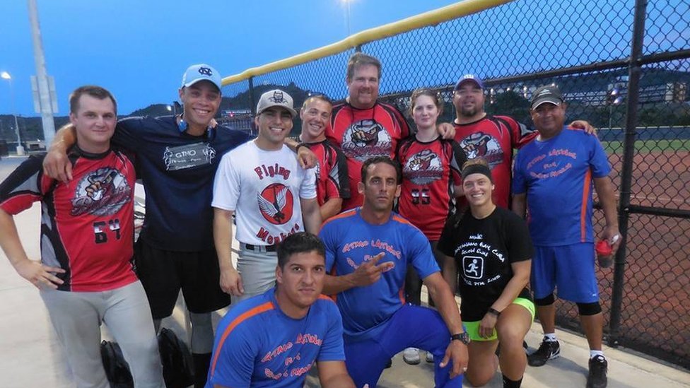 Ridel e Richard, no centro da imagem de camisa azul, posam com outras pessoas após um jogo de beisebol