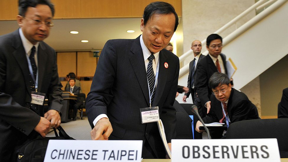 Министр здравоохранения Тайваня Е Чинг-чуань (К) занимает место перед открытием ежегодного собрания Всемирной организации здравоохранения (ВОЗ) 18 мая 2009 года в офисе Организации Объединенных Наций в Женеве. Тайвань впервые был приглашен на ежегодное собрание Всемирной ассамблеи здравоохранения в качестве наблюдателя.