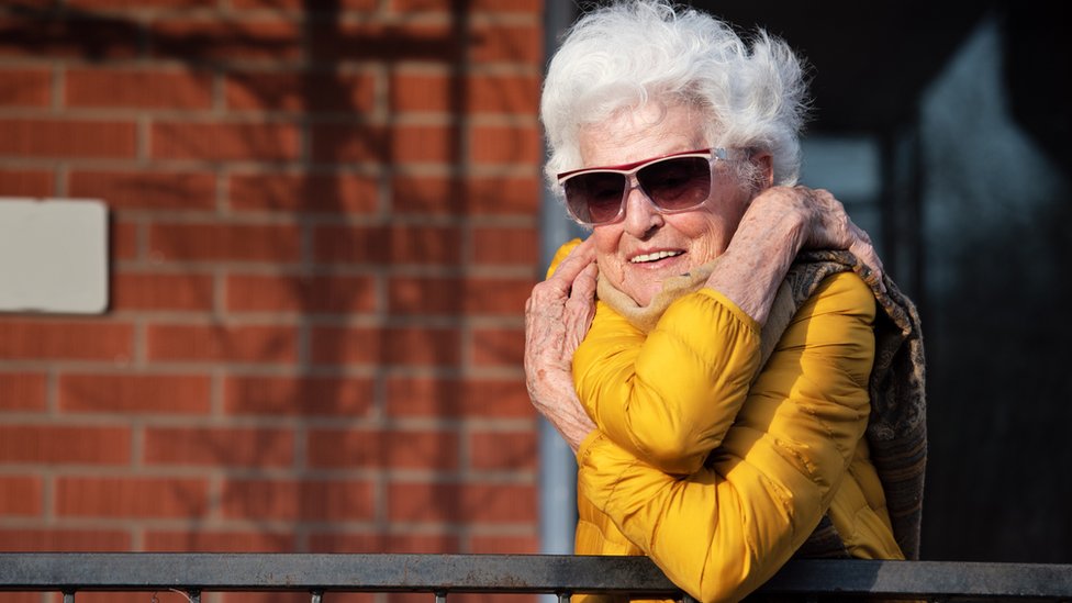 An older lady in isolation hugs herself