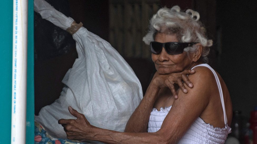 Una mujer asomada a la ventana con una bolsa de ayuda en Panamá