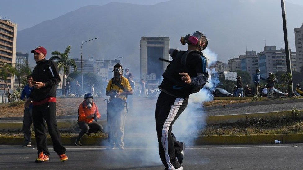 Un manifestante intenta lanzar una lata de gas lacrimógeno Un manifestante intenta lanzar una lata de gas lacrimógeno
