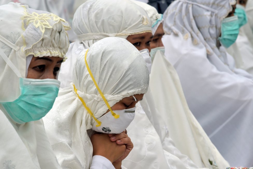 Индонезийские женщины в масках молятся в Пеканбару 15 сентября 2015 года.