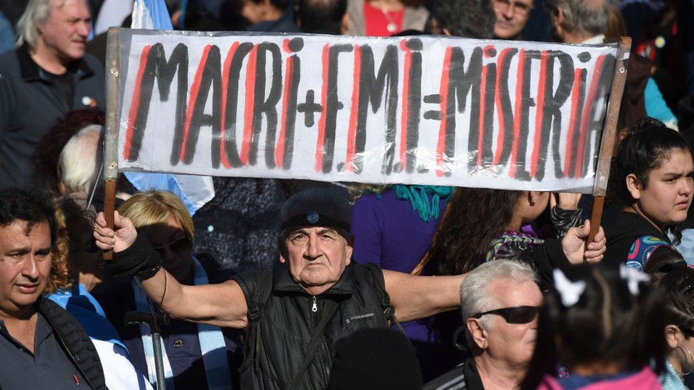 Hombre sostiene un cartel con la leyenda: Macri+FMI=Miseria.