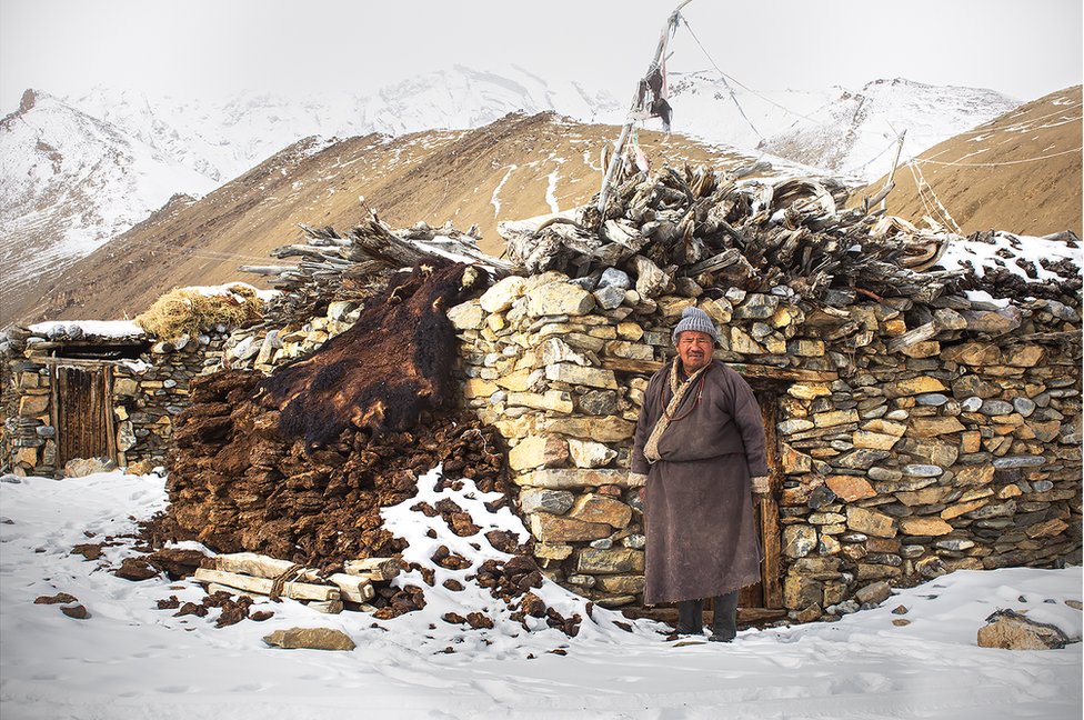 Пастух стоит перед своим каменным домом