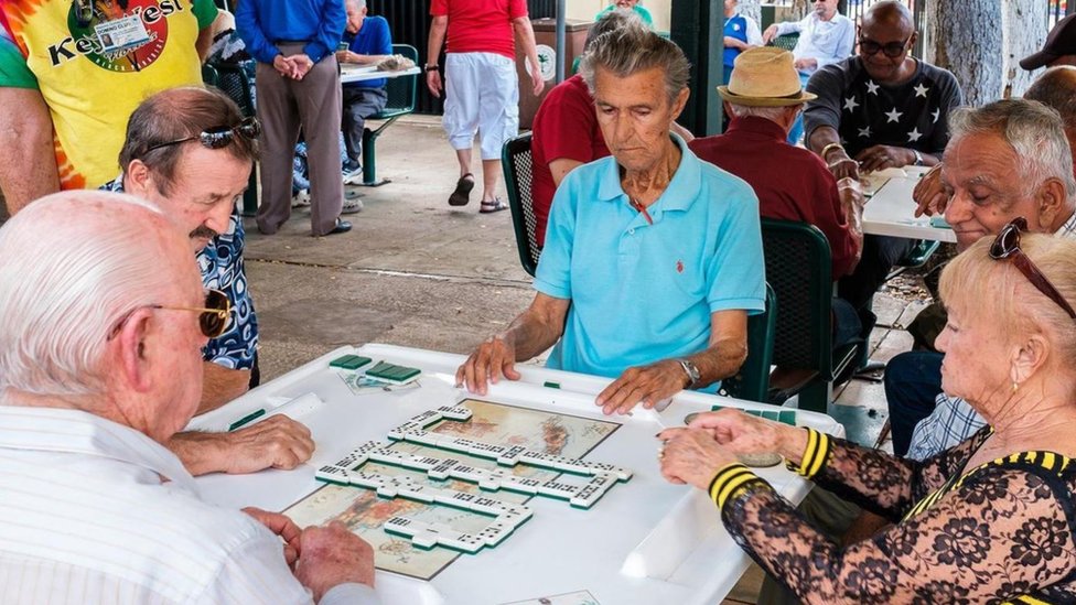 Un grupo de adultos mayores jugando dominó