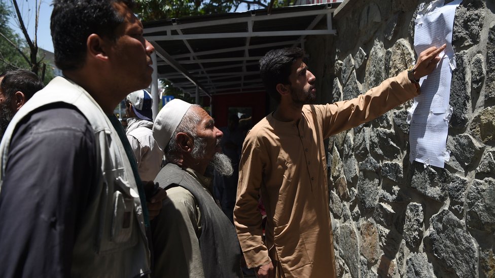 Мужчины проверяют список погибших после взрыва автомобиля в Кабуле 1 июля