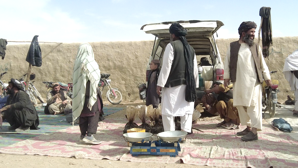 Kandahar'daki pazarda tartılar ve torbaların içindeki satılık afyon sakızları da görülüyor