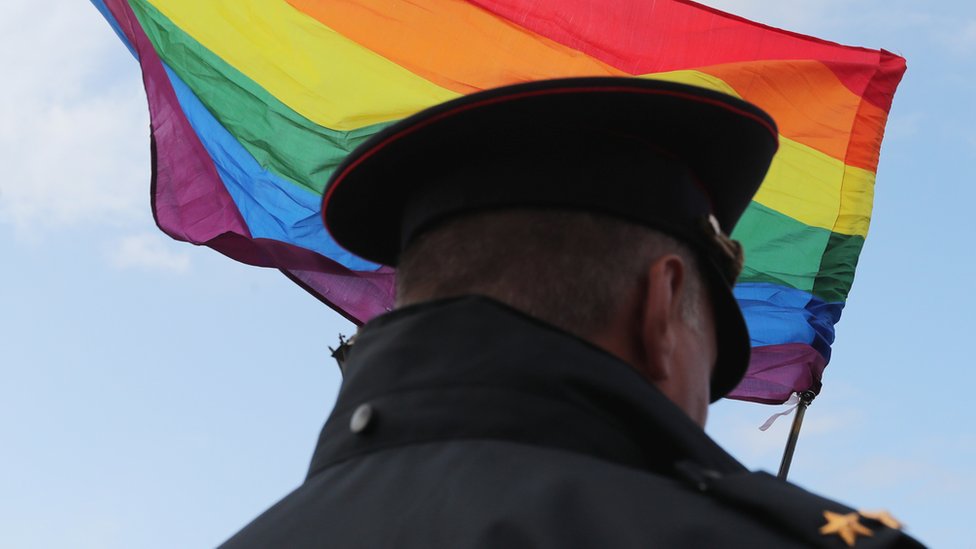 A Russian police officer and the rainbow pride flag in the background. File photo