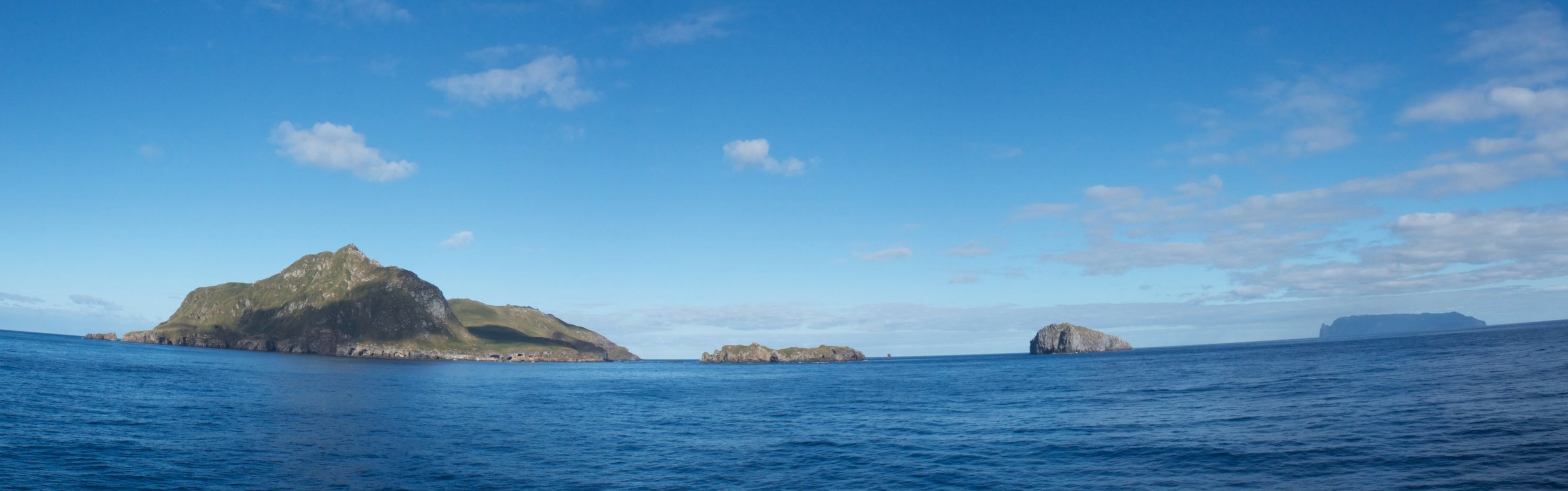 Panoramic views of Nightingale Islands, with the dark outline of Inaccessible Island in the distance