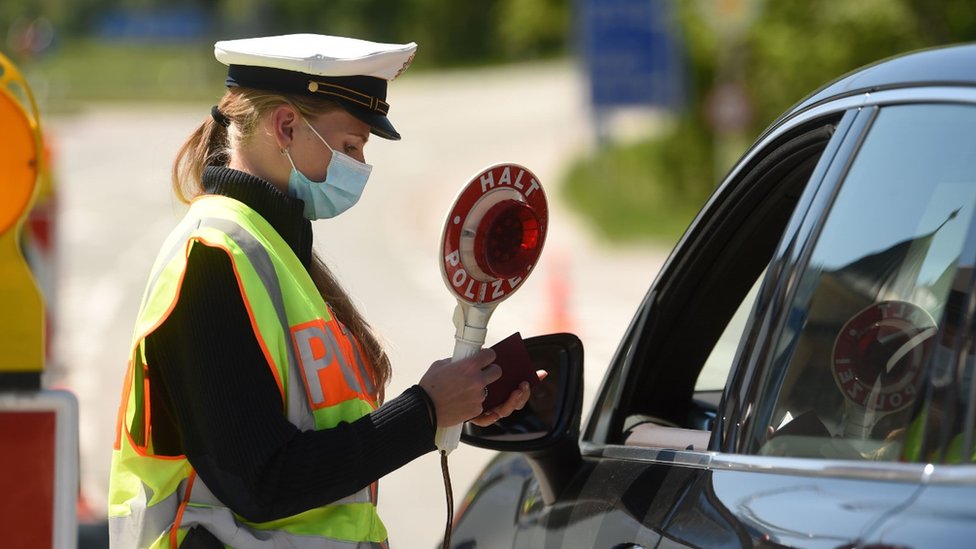 Немецкий полицейский в защитной маске во время контроля за автомобилем на пограничном переходе между Австрией и Германией, недалеко от немецкой деревни Обераудорф