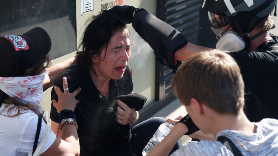 Протестующему, пострадавшему от воздействия слезоточивого газа, помогает журналист