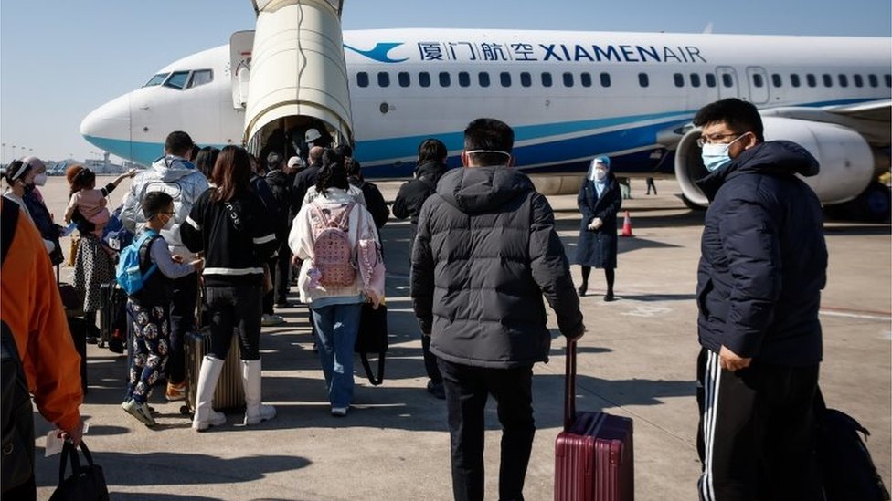 Passengers bound for Beijing board an airplane at the Xiamen Gaoqi International Airport in Xiamen, Fujian province, China, 26 December 2022.