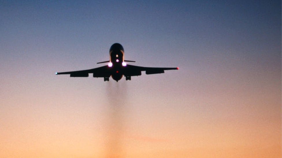 Un avión de pasajeros dejando una estela de humo a su paso.
