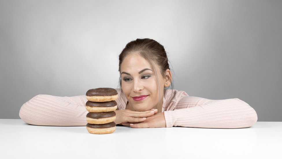 Mujer mirando una torre de donuts.