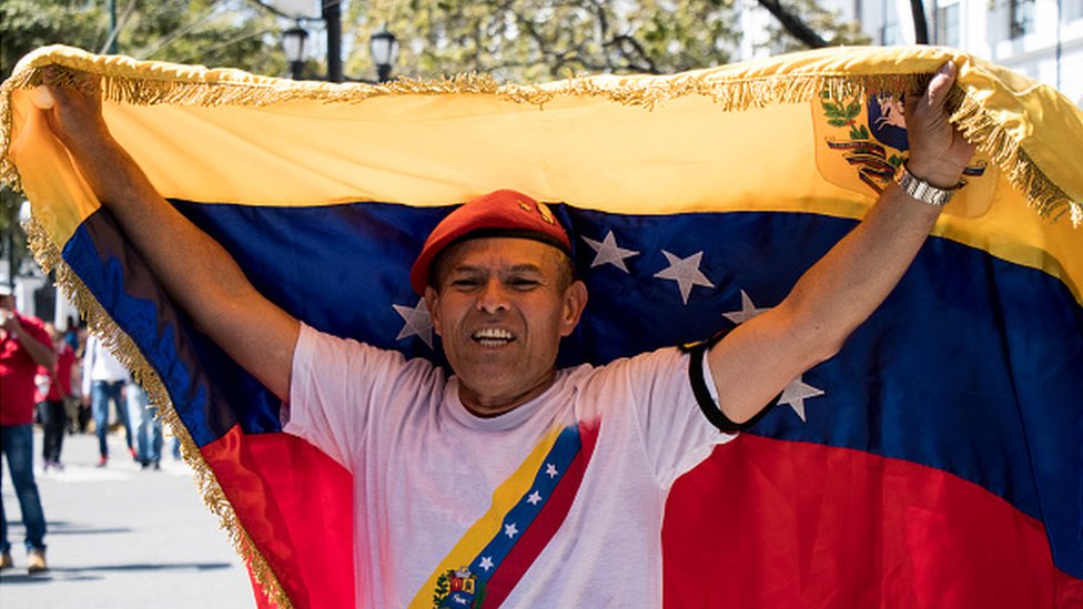 Un hombre ondea la bandera venezolana